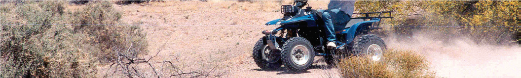 man in blue jeans drives ATV on narrow dirt road