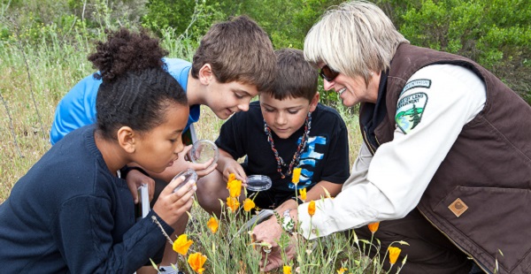 Young explorers examine poppies with magnifying glasses. Photo by Bob Wick, BLM.