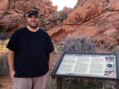 Ryan Chatterton stands in front of red sandstone cliffs. Photo by BLM. 