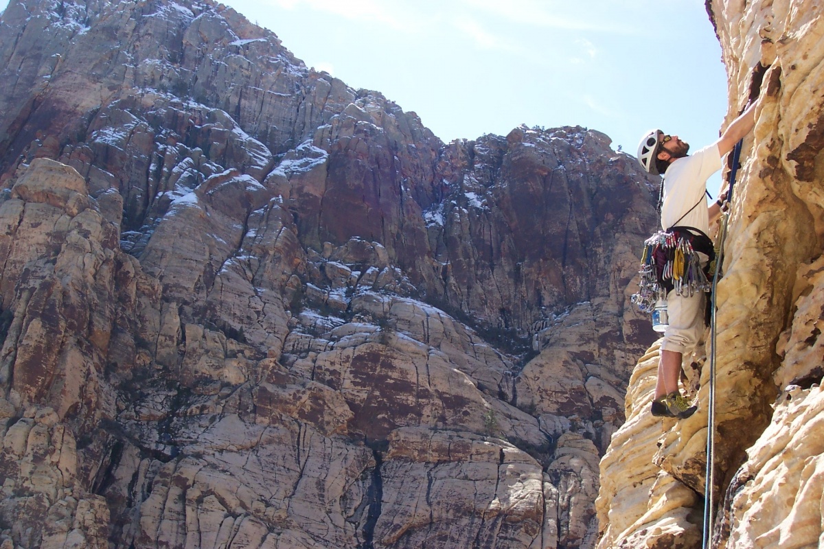 A rock climber ascends a white cliff.