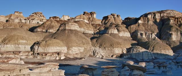 The landscape of sandstone cap rocks and scenic olive-colored hills with an interesting array of hoodoos and other formations in Ah-Shi-Sle-Pah Wilderness in New Mexico.