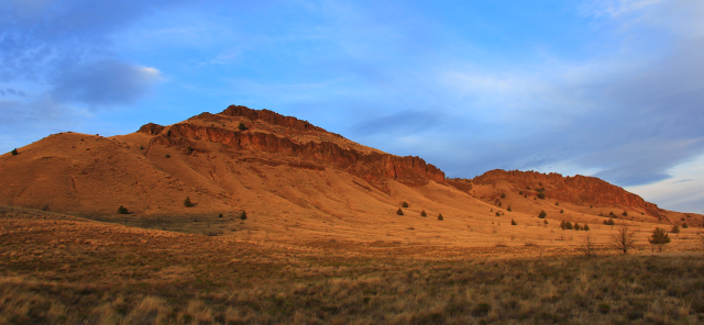 Spring Basin landscape showing red rolling hills and native plants