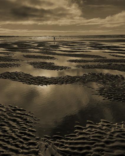 photo by Darryl Baird of a person walking along the ocean