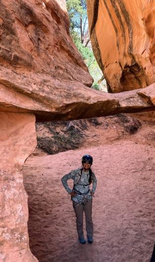 A woman stands beneath red rock towers