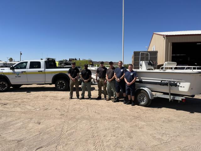 Six people standing in front of a BLM truck and a boat.
