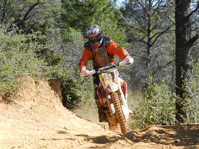 A person rides a dirt bike on a trail in a forest.