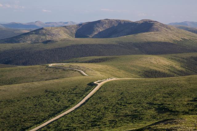 An access road weaves through hilly terrain.