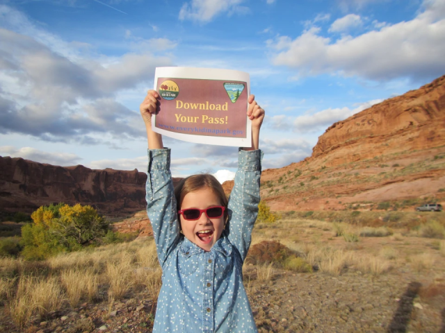 Fourth grader standing in a canyon landscape advocating to download the Every Kid Outdoors Pass