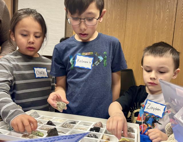 A photo of three children looking at a rock display.