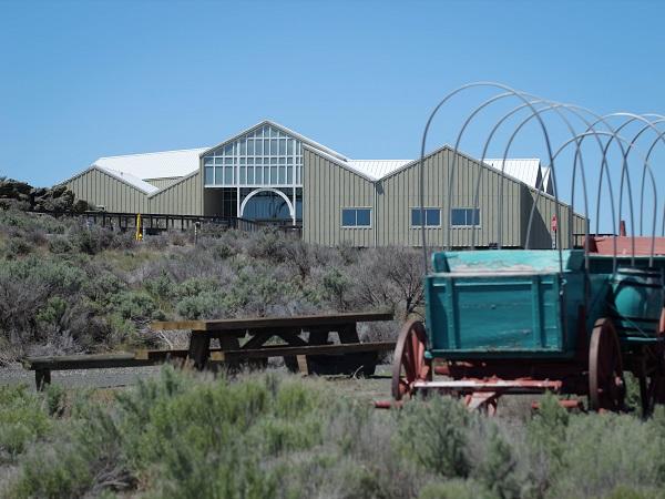 front view of the entrance of the National Historic Oregon Trail Interpretive Center with old fashion covered wagons in the foreground