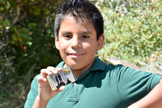 A child holds up their Fourth Grade Every Kid Outdoors Park Pass