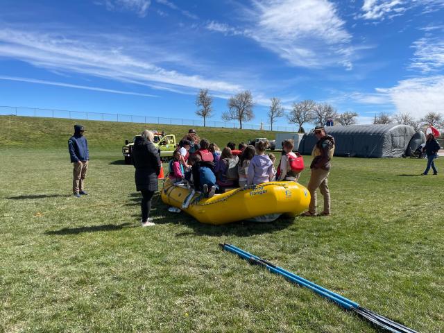 Students gather in an inflatable raft in a field with BLM staff standing nearby.