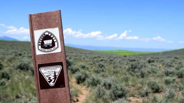 Signage for the Bureau of Land Managmenet and Department of Interior on a metal post in front of an open landscape