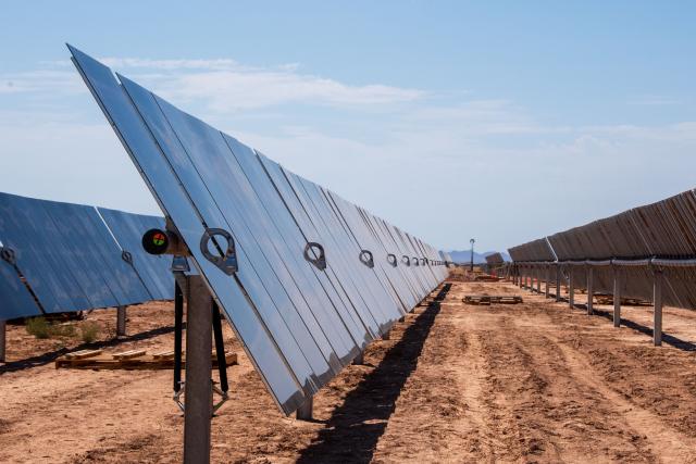 Rows of newly constructed solar panels in a dirt field.