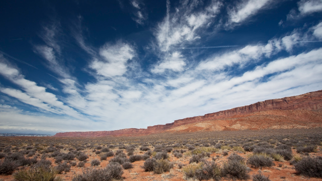 Blue sky with scattered clouds over a sprawling landscape covered in desert vegetation.
