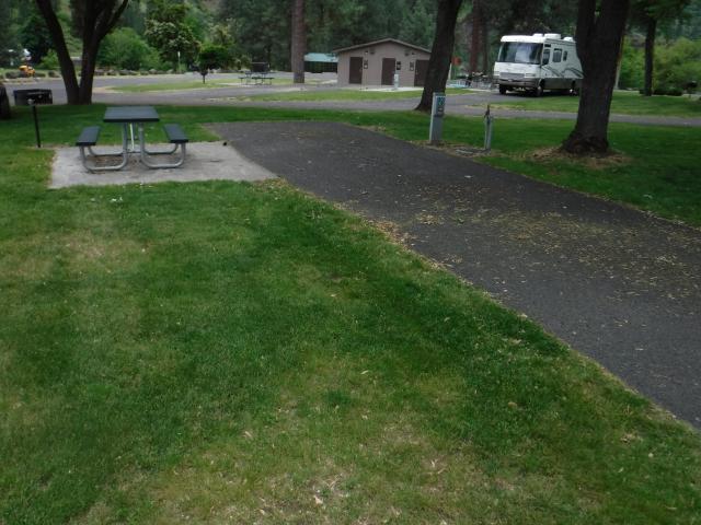 Recreational vehicle site at Mckay's Bend Campground. Grass, picnic bench in foreground.  RV and bathrooms in background.