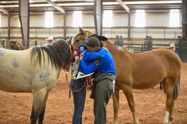 WHB Fest 2024 Day 2 – The first and second place contestants hug one another. Emotions ran high as the winners were announced and the trainers prepared to auction their horses to the crowd.