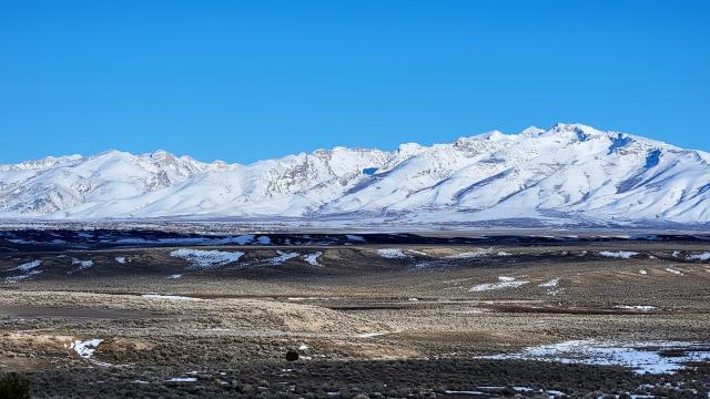 a snowy mountain range above a sagebrush landscape