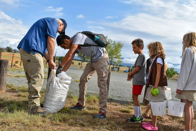 Michael McGee, left, a hydrologist in the Roswell Field Office, distributes grass seed to volunteers.