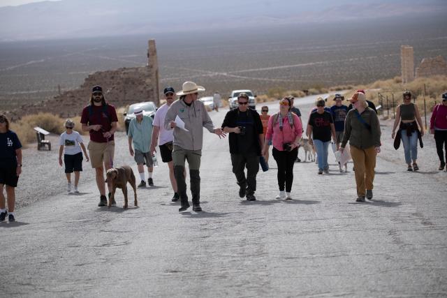 A group of people walk uphill led by two uniformed guides.