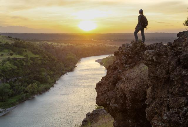 a hiker overlooks a sunset from a cliff