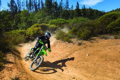 A dirt bike takes a turn between two chaparral covered foot hills.