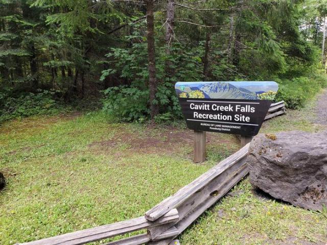 wooden sign outdoors near a fence reading Cavitt Creek Falls Recreation Site