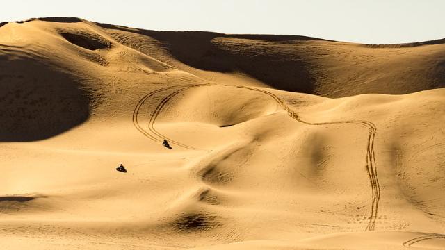 two OHVs ascend a large sand mountain