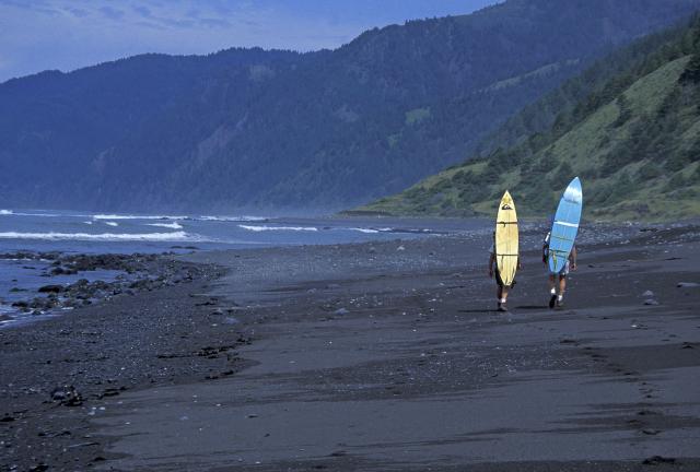 two surfers on a rocky beach