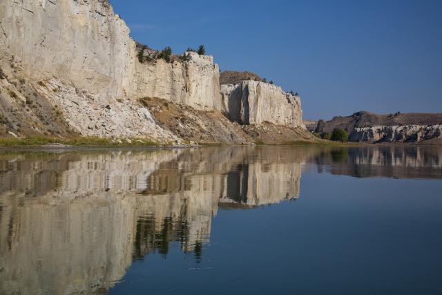 a white cliff overlooks a river