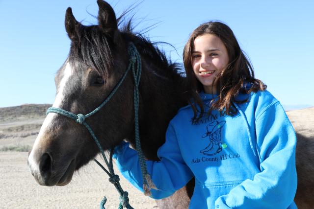 A 4-H member showcases her young wild horse charge prior to a trail challenge event. 