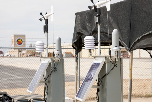 Two machines with solar panels, gray metal boxes, antennae, and wind catchers. 