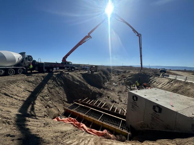 Concrete trucks pouring footers and wing walls at a box culvert location