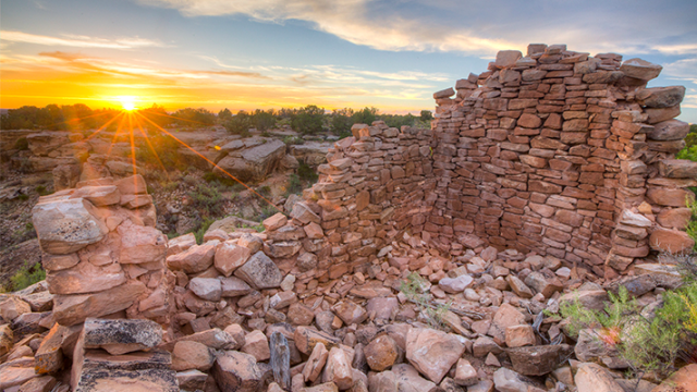 The sun rises over stone ruins.