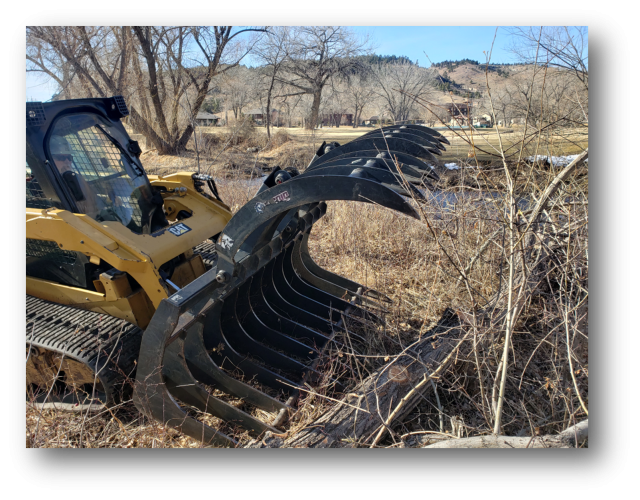 Heavy machinery with large jaws pushing a pile of brush