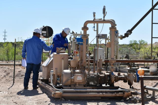 Two petroleum engineering technicians are inspecting equipment. 