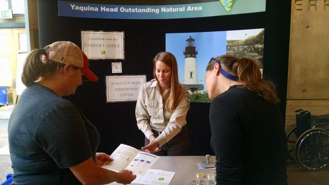 Group of people looking over a display table at which a park ranger stands