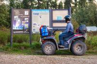 A rider on an ATV looks at the trailhead information kiosk.