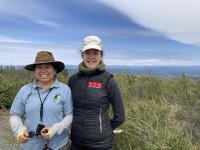 BLM’s Pine Hill Preserve Manager Graciela Hinshaw stands with Margaux Blanc. A field of brush is in the background. 