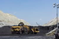 A large yellow truck is being loaded with large amounts of black coal by a small construction vehicle. 