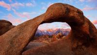 A granite arch with tall mountains in the background.