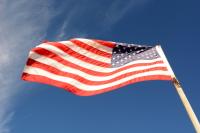 An American flag blows in the wind with blue skies in the background