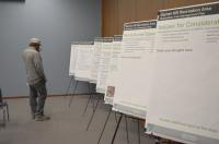 A member of the public looks at display boards during a public meeting.