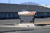 A blue sky and snow-capped mountain are the background for the Battle Mountain District Office with its Bureau of Land Management sign in front.
