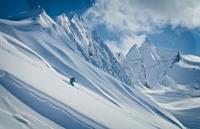 Image of a skier coming down a snowy steep mountain slope.