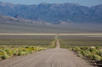 A gravel access road leading to a mountain range.