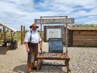 Wyoming blacksmith Dave Osmundsen stands next to an event schedule board. 