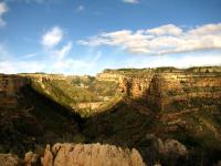Scenic photo of a deep canyon with blue sky, clouds in background. 