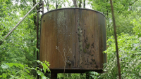 A large rusting tank, part of an orphaned well, stands in heavy forest near the Shenango River Lake in northwestern Pennsylvania.