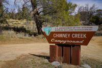 A brown trapezoid sign reading Chimney Creek Campground.